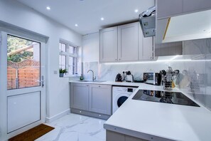 Una cocina moderna con lavadora, fregadero y armarios.
