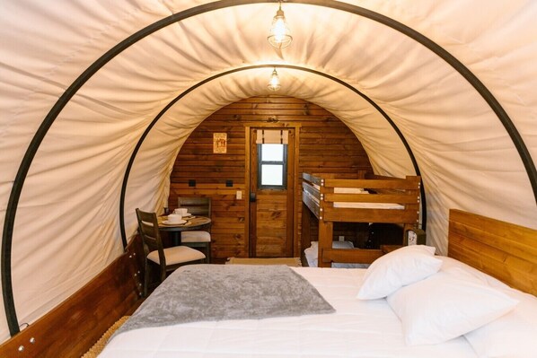 A tent with a bunk bed, a table with chairs, and a window.