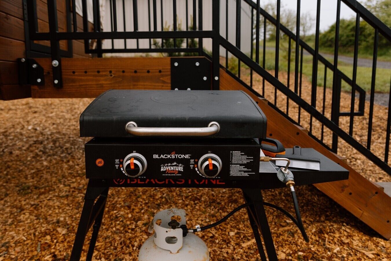 A portable grill with a handle, control knobs, and a gas cylinder.