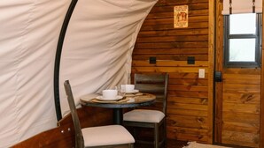 Un interior de madera acogedor con una mesa redonda para dos personas, una silla y una puerta con ventana.