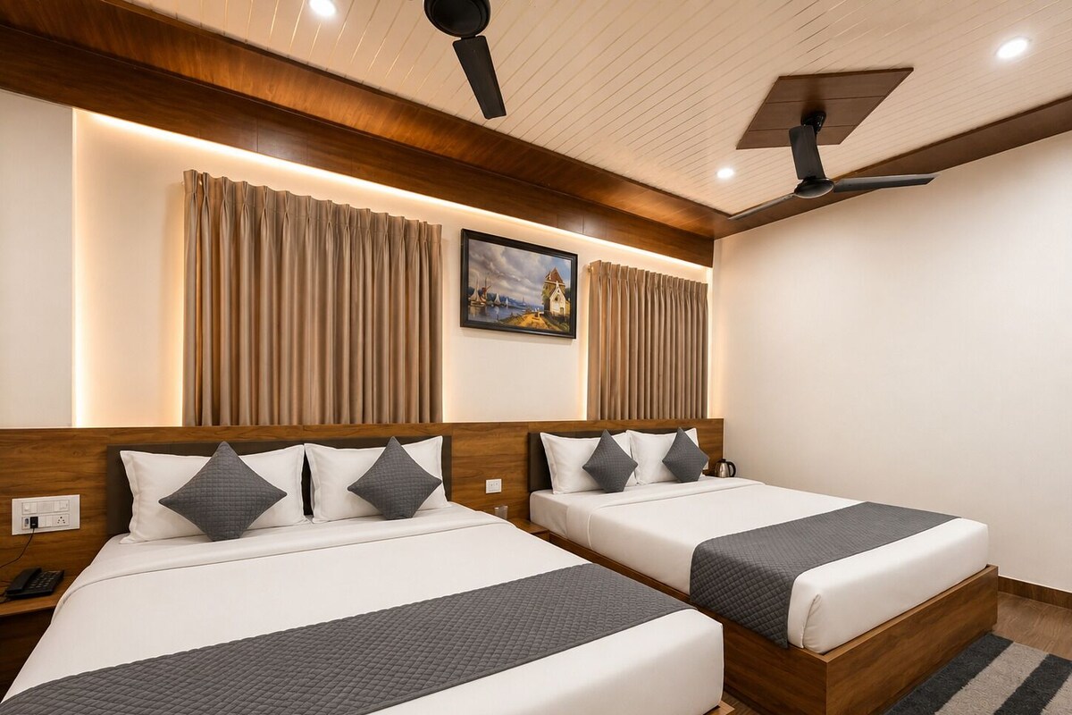 Een hotelkamer met twee bedden, houten hoofdborden, een schilderij aan de muur en een plafondventilator.