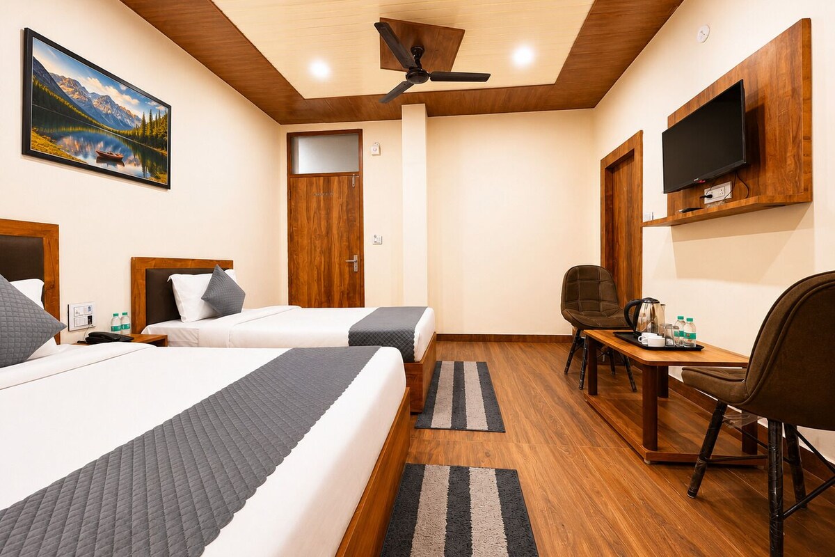 Een hotelkamer met twee bedden, een bureau, een stoel, een televisie en een schilderij aan de muur.
