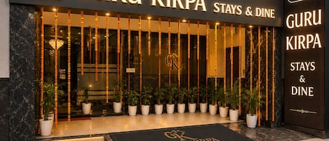 Entrada de un hotel con un letrero que dice 'GURU KIRPA STAYS & DINE'.