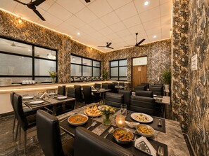Een restaurant met een marmeren wand, plafondventilatoren en een buffet.
