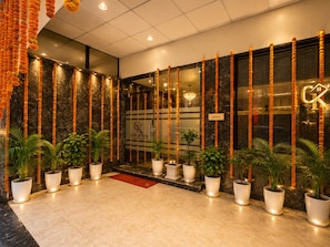 Een hotelentree met een glazen deur, plantenbakken en een bord dat aangeeft dat het hotel geopend is.