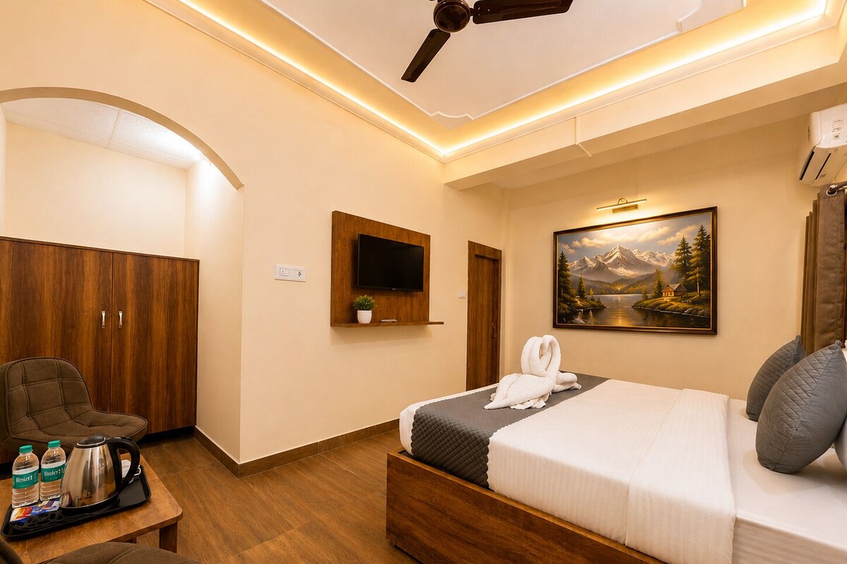 Een hotelkamer met een bed, een televisie, een schilderij, een kledingkast en een zithoek met een tafel.