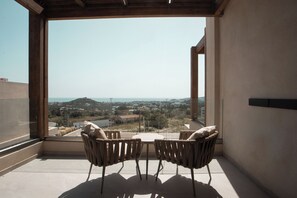 Ein Balkon mit Blick auf eine Stadt und Hügel, ausgestattet mit zwei Stühlen und einem Tisch.