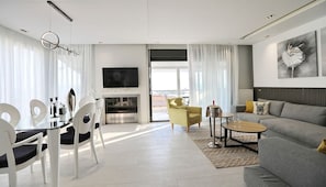 A modern living room with a sofa, dining table, chairs, a fireplace, and a television. - Heaven Horizon Villa - Ethereal and Blissful Gem (Pangaio)