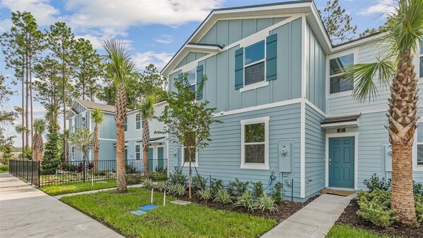 A residential building with a light blue exterior, multiple windows, and a front door. - 2-bedroom townhome in St. Augustine (St. Augustine)