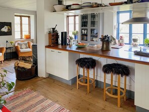 A kitchen with wooden countertops, white cabinets, and two stools with black fur-like seats. - Farm on Gotland with fruit trees near harbour (Slite)