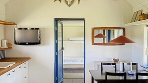 Moderni keittiö, jossa on televisio, puukaapit, ruokailutila pöytineen ja tuoleineen sekä suuri hirvenpääaiheinen koriste seinällä.