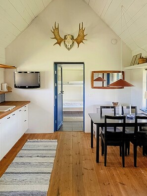 A modern kitchen with a TV, wooden cabinets, a dining area with a table and chairs, and a large antler decoration on the wall. - Farm on Gotland with fruit trees near harbour (Slite)