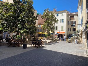 Eine Kopfsteinpflasterstraße mit Außenbestuhlung, einem Café und Gebäuden mit Balkonen.