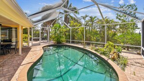 A pool area with a glass ceiling, outdoor seating, and surrounding greenery. - Sunnyside Up Cottage - Walk to Siesta Beach, Waterfront Home by The Bay & Key Collection (Siesta Key)