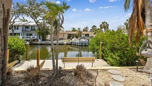 A waterfront property with a dock, a bench, and a small garden area. - Sunnyside Up Cottage - Walk to Siesta Beach, Waterfront Home by The Bay & Key Collection (Siesta Key)