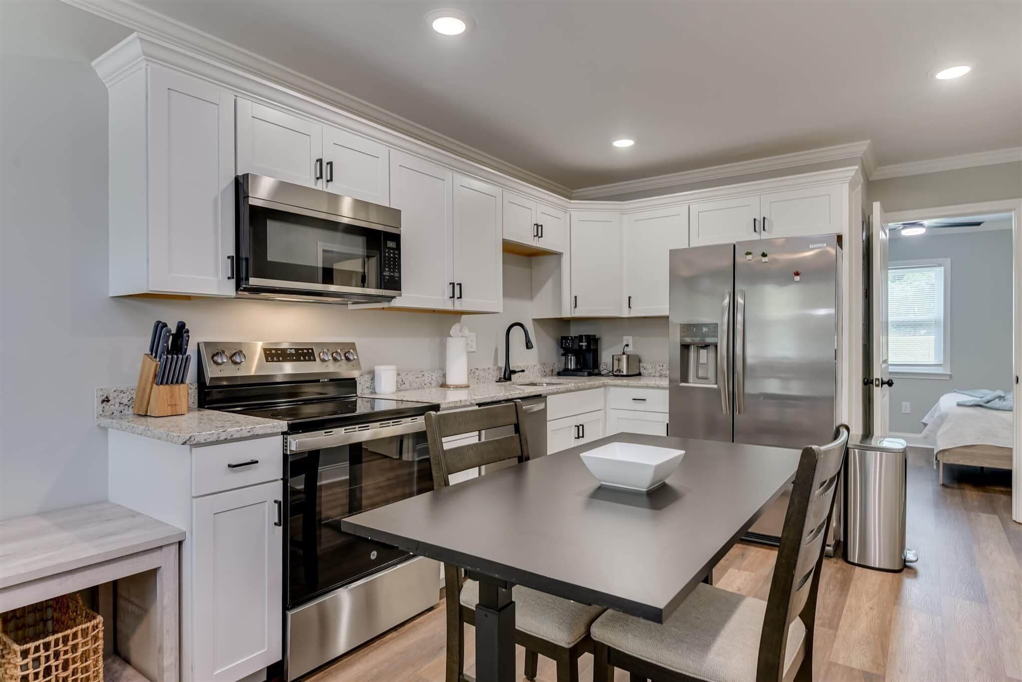 A modern kitchen with white cabinets, stainless steel appliances, and a central island with seating.