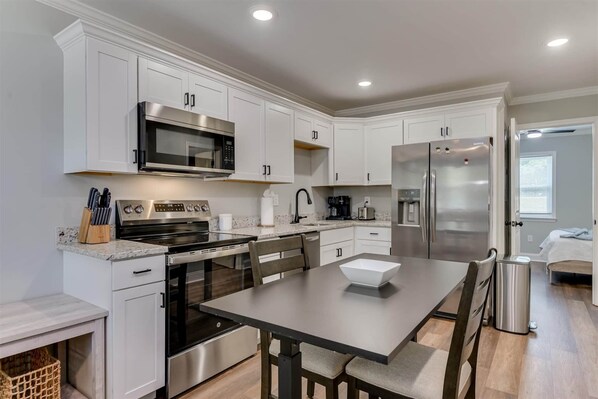 A modern kitchen with white cabinets, stainless steel appliances, and a central island with seating.