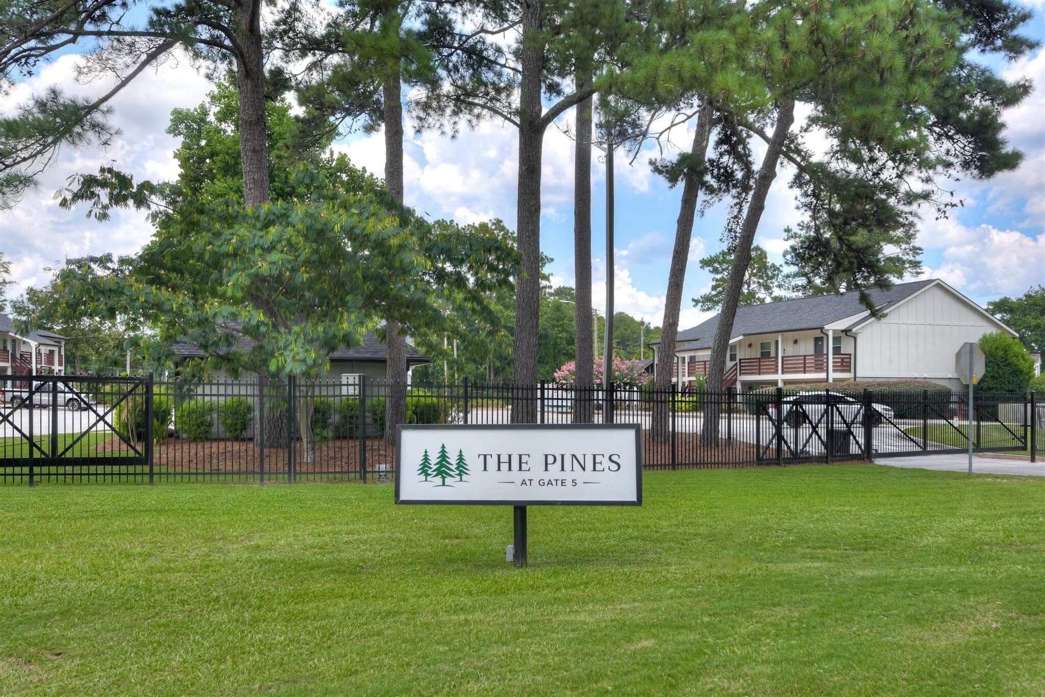 Un conjunto residencial cerrado llamado 'The Pines' con un letrero que indica 'En la puerta 5'.