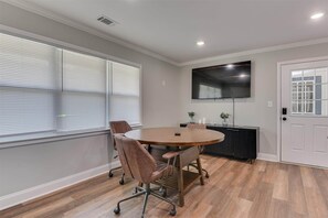 A conference room with a round table, chairs, a TV, and a door. - Pines at 5 Corporate Furnished Rentals Suite 214 (Hephzibah)