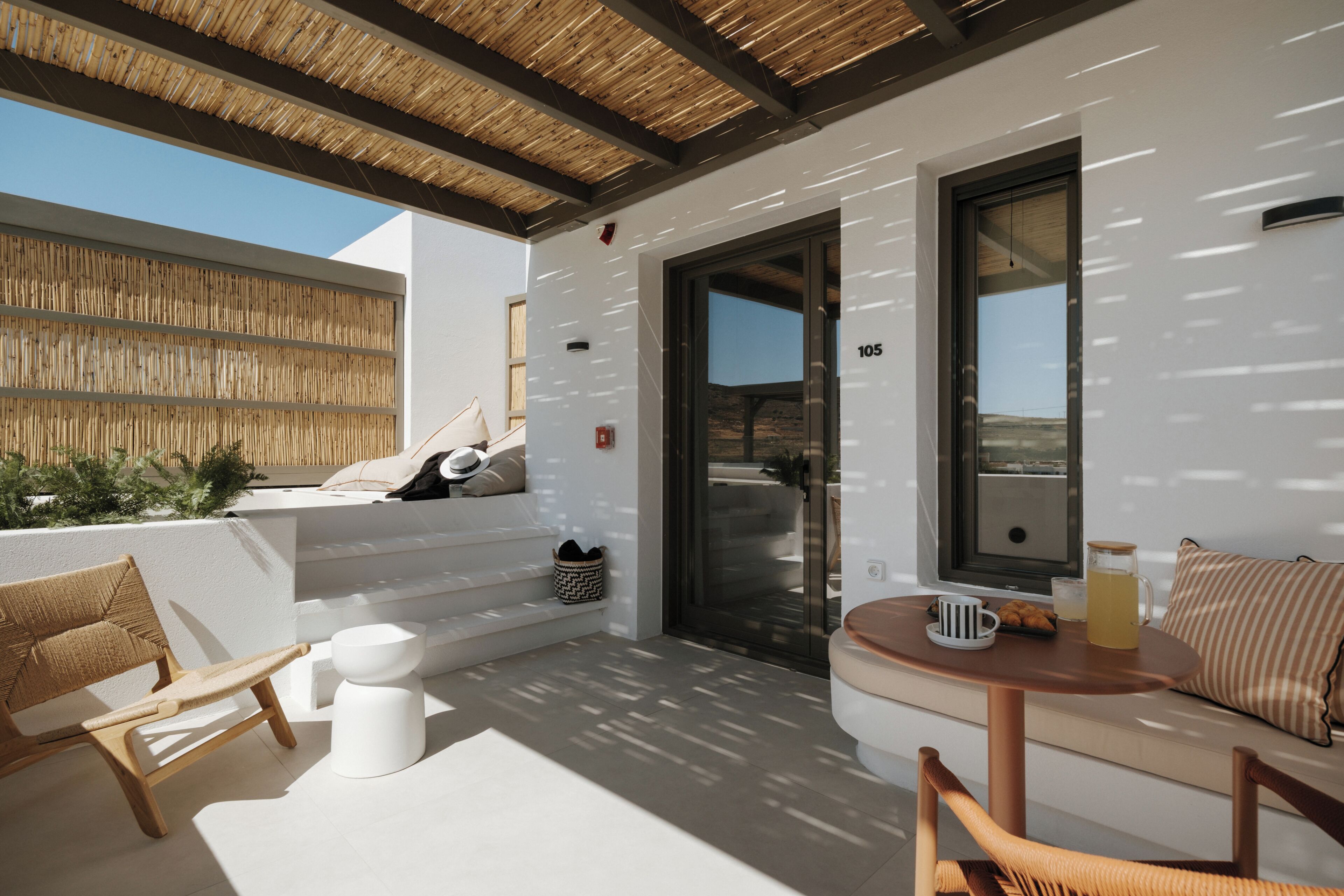 Un espacio moderno al aire libre con un muro blanco, techo de madera y vistas al paisaje.