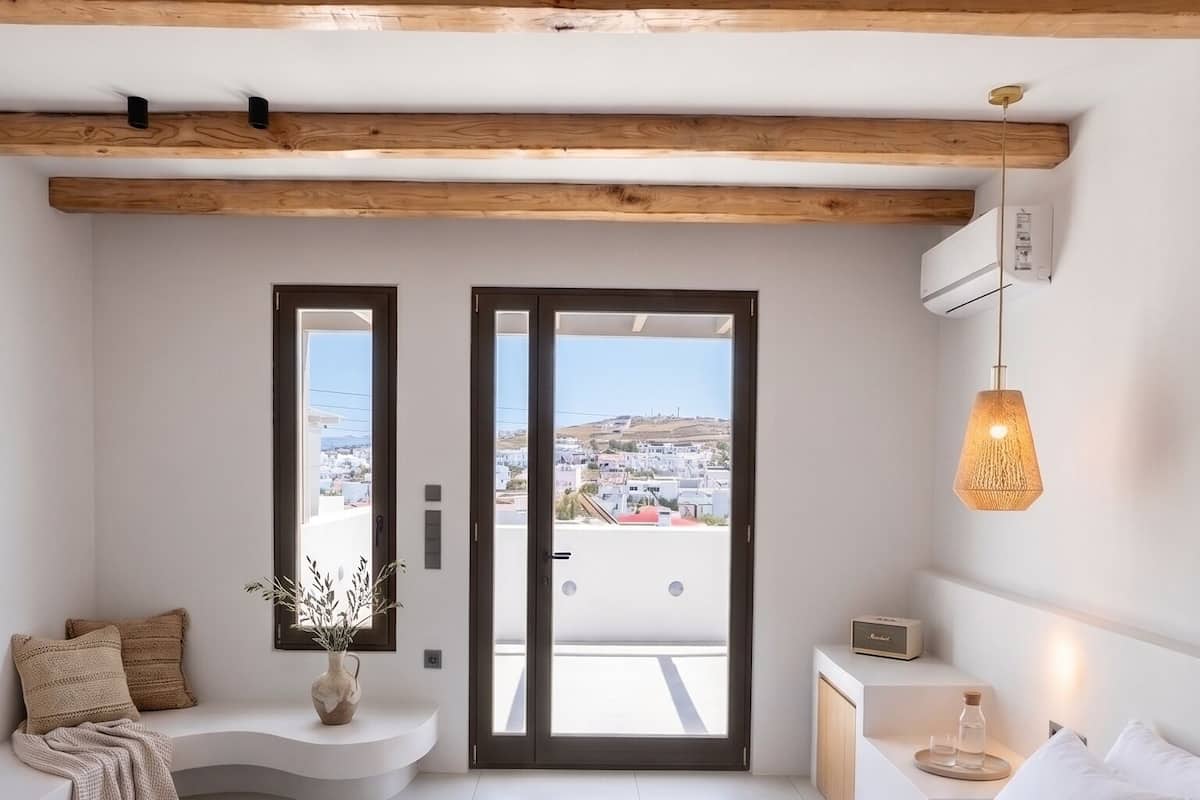 A modern bedroom with a large bed, a view through a door, and a hanging light fixture.