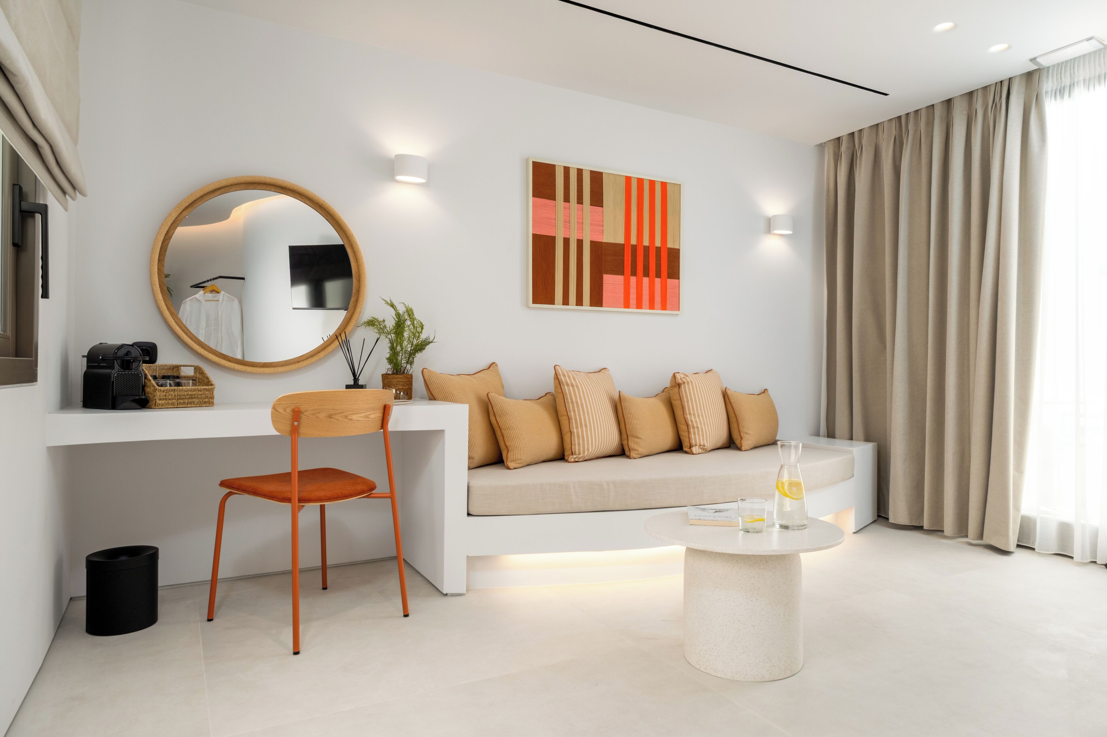 Ein modernes Wohnzimmer mit einer Couch, einem runden Couchtisch, einem Sessel, einem Spiegel und einem Gemälde an der Wand.
