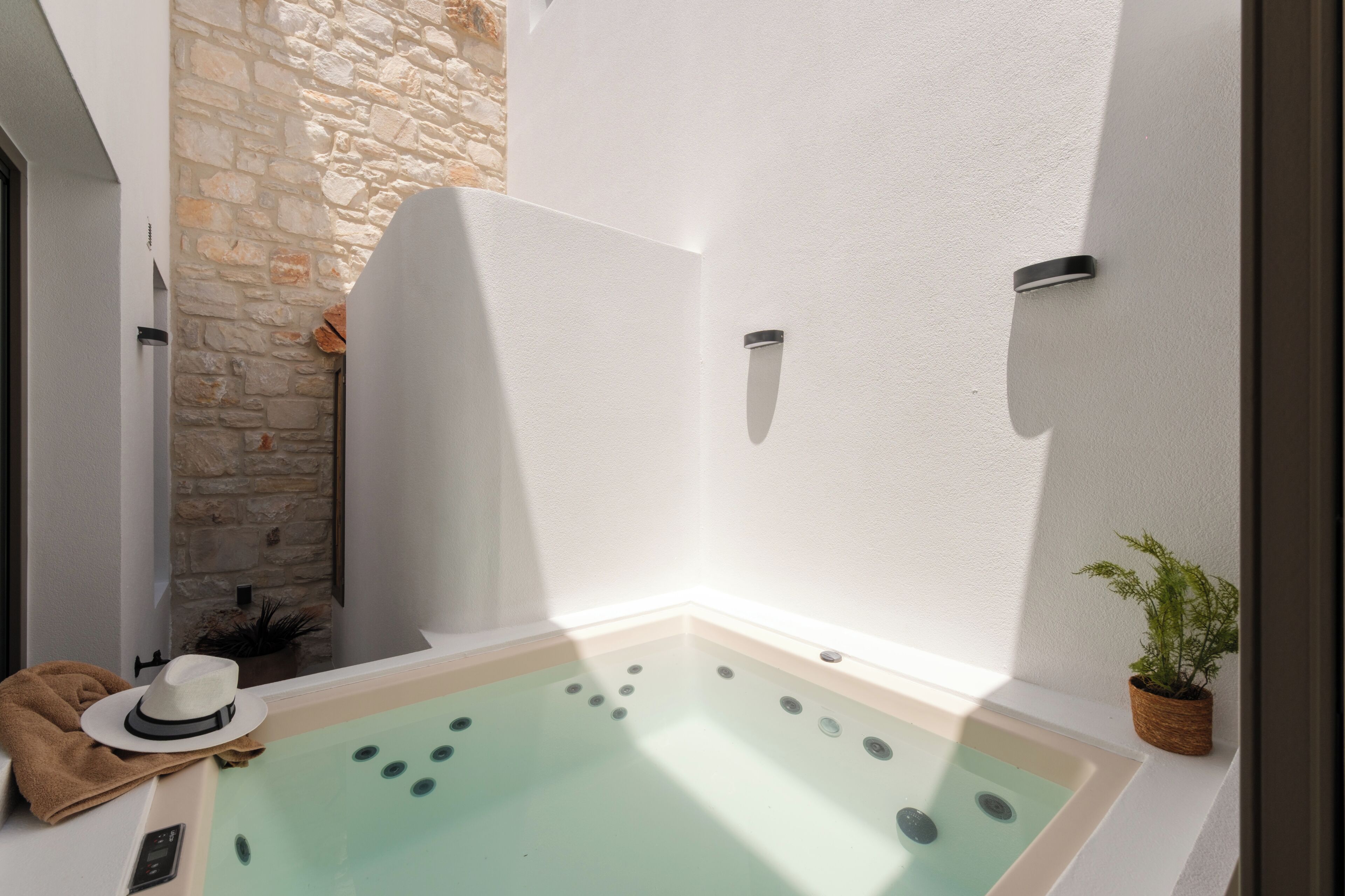 A spa area with a stone wall, a bathtub, and a potted plant.