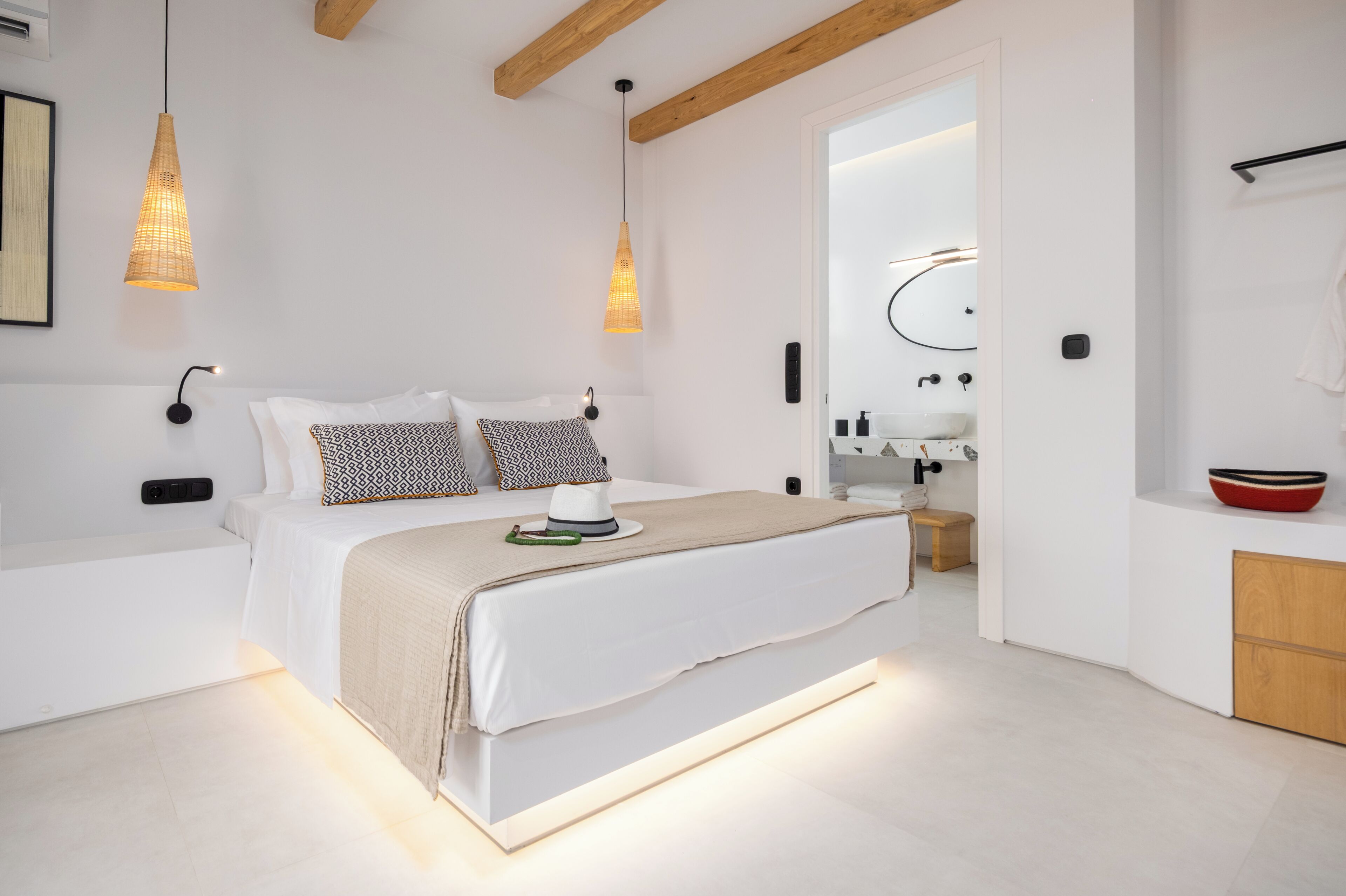 A modern bedroom with a large bed, bedside lamps, a bedside table, and a built-in bench.