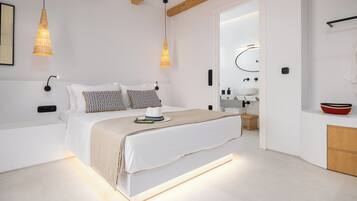 A modern bedroom with a large bed, bedside lamps, a bedside table, and a built-in bench.