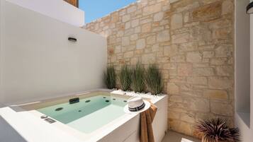 A spa area with a stone wall, a hot tub, and decorative plants.