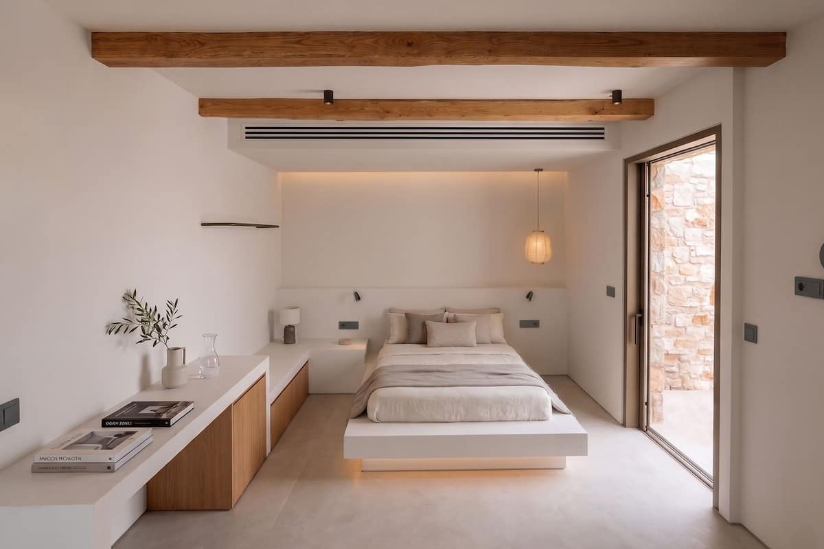A modern bedroom with a minimalist design, featuring a bed, bedside tables, a built-in bench, and a large window.