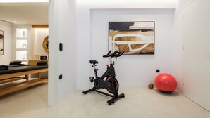 A modern room with a stationary bike, a red exercise ball, and a large abstract painting on the wall. - The Lofts Paros Executive Suites (Naousa)