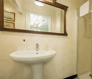 Un bagno con un lavandino bianco, uno specchio e un quadro appeso alla parete.