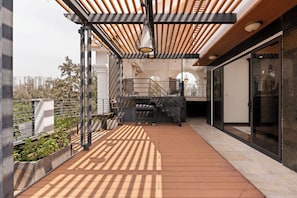 A modern outdoor balcony with a wooden ceiling, metal railings, and a view of the cityscape. - Mia Riverside Villa D7 with 9 bedrooms (Ho Chi Minh City)