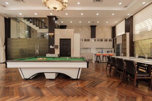 Un intérieur moderne comprenant une table de billard, un coin repas, une cuisine et un escalier.