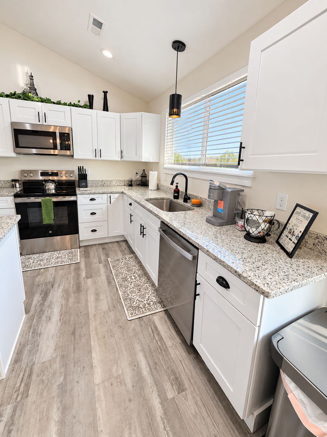 A modern kitchen with white cabinetry, stainless steel appliances, and a granite countertop.