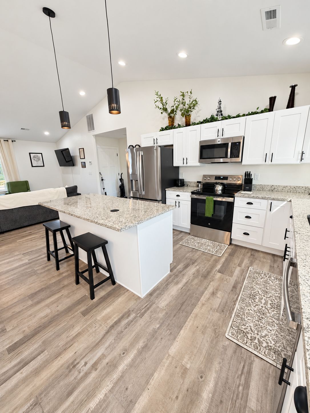 A modern kitchen with white cabinets, stainless steel appliances, and a marble countertop.