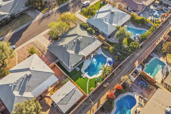 An aerial view of a residential area with multiple houses, each with a swimming pool and a well-maintained lawn. - Picture-perfect Getaway w/ Remodeled Bath! (Scottsdale)