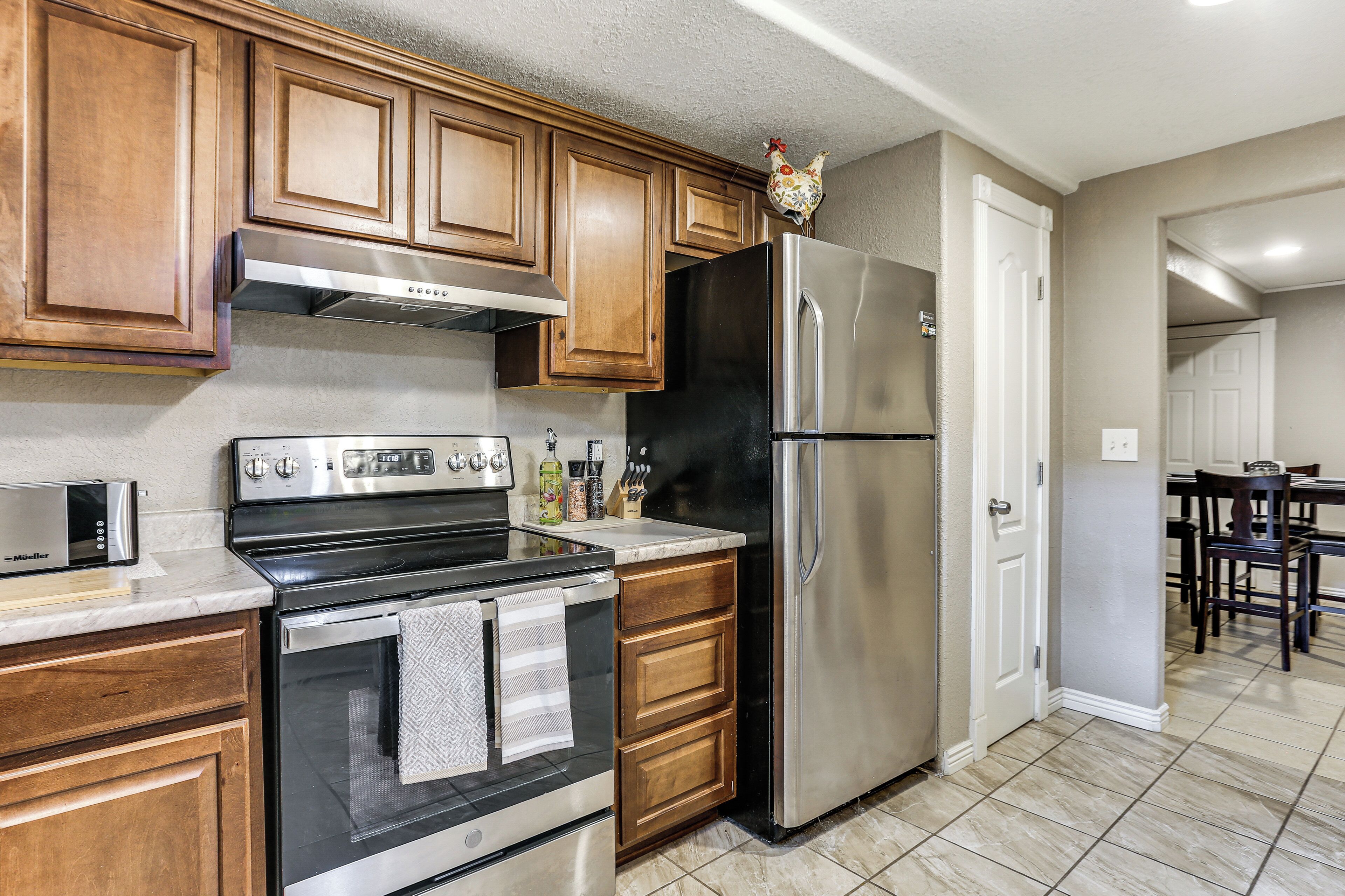 A kitchen with wooden cabinets, a stainless steel refrigerator, a built-in oven, and a microwave.