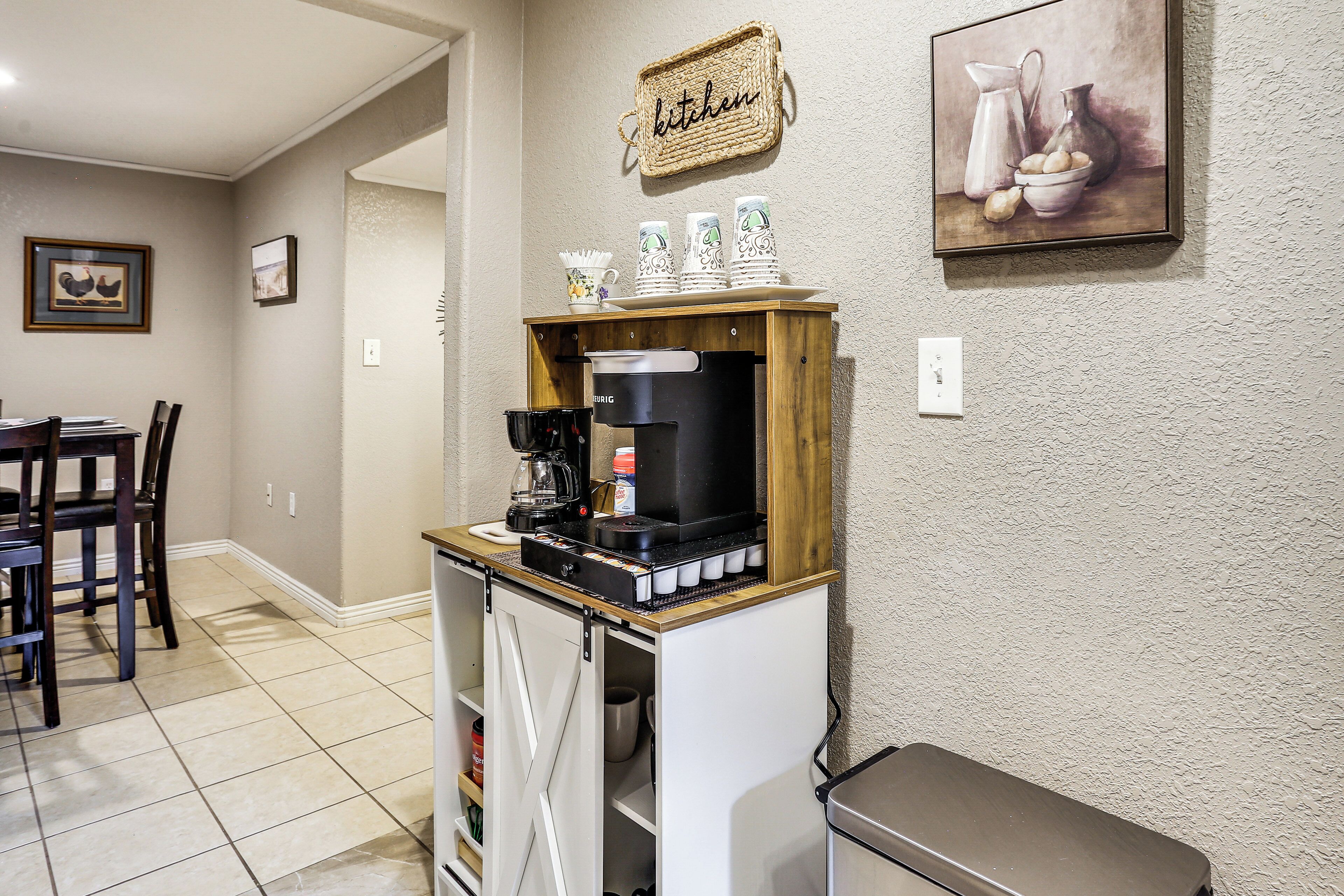 A kitchen area with a coffee machine, a wooden cabinet, and a wall-mounted sign.