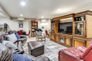 Un salon avec des canapés en cuir, un fauteuil rouge, un meuble en bois et un téléviseur.
