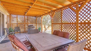 An outdoor patio with a wooden table and wicker chairs, surrounded by a wooden lattice fence. - 7 Miles to Roosevelt Lake! Mtn-view Family Escape (Tonto Basin)