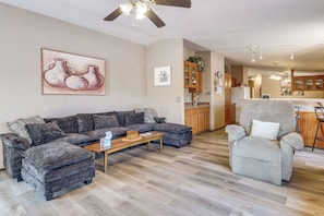 A living room with a sectional sofa, a recliner, a wooden coffee table, and a ceiling fan.