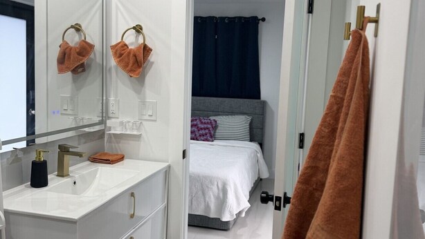 Une salle de bain moderne avec un meuble-lavabo blanc, un grand miroir et un porte-serviettes.
