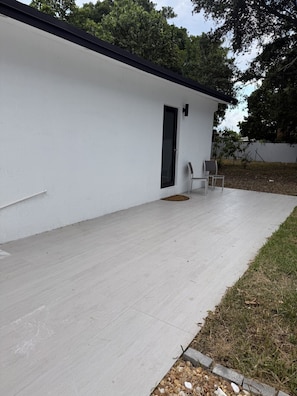 A modern building with a flat roof, a concrete patio, and a door.