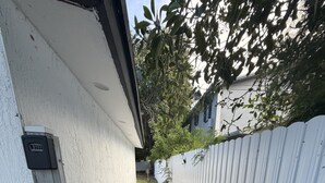 Un sentier étroit recouvert de gravier, une clôture blanche et un portail en métal.