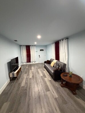 Ein Wohnzimmer mit einer Couch, einem Couchtisch, einer TV-Bank und einer TĂŒr.