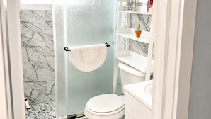 Un bagno con doccia, toilette e pareti con decoro marmorizzato.
