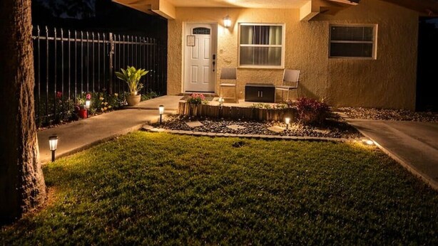 Una casa a due piani con un portico, un garage e un prato ben illuminato di notte.