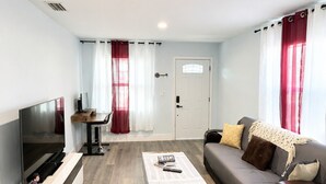 Un salon moderne doté d’un téléviseur à écran plat, d’un canapé, d’une table basse et d’un coin repas avec une table et des chaises.